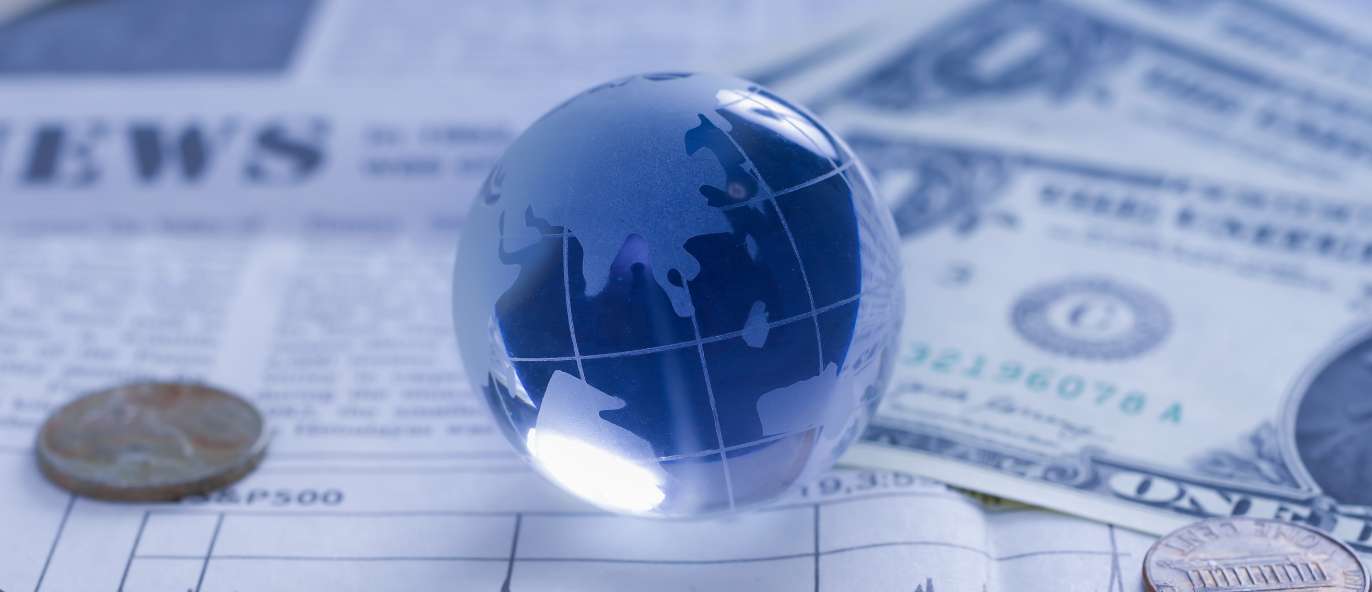 Glass globe sitting on investment paperwork and dollar bills