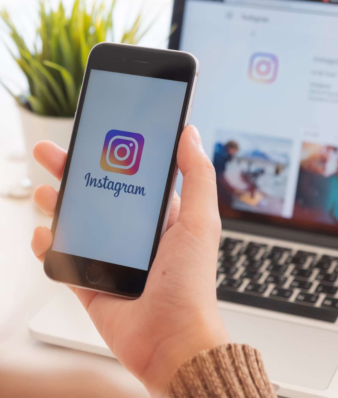 Person sitting at a computer with a phone open to Instagram - Direct Online Marketing internet marketing company - Provider of Instagram Marketing Services